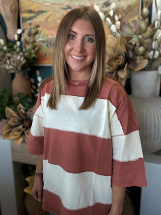 Woman wearing an oversized toasted almond and ivory color block knit top with medium wash jeans