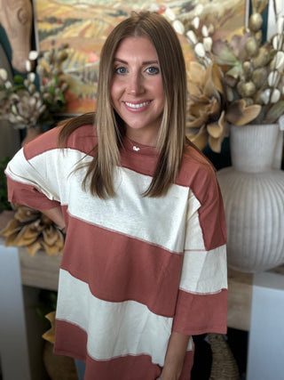 Woman wearing an oversized toasted almond and ivory color block knit top with medium wash jeans