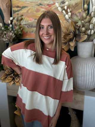 Woman wearing an oversized toasted almond and ivory color block knit top with medium wash jeans