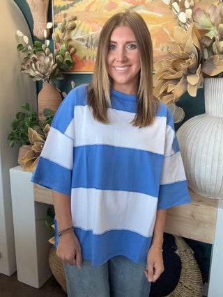 Woman wearing an oversized sky blue and white color block knit top with light wash jeans