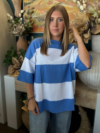 Woman wearing an oversized sky blue and white color block knit top with light wash jeans