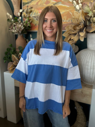 Woman wearing an oversized sky blue and white color block knit top with light wash jeans