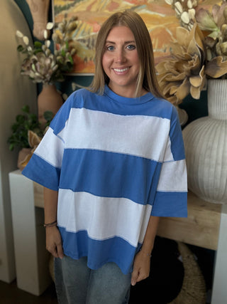 Woman wearing an oversized sky blue and white color block knit top with light wash jeans