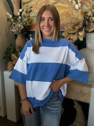 Woman wearing an oversized sky blue and white color block knit top with light wash jeans