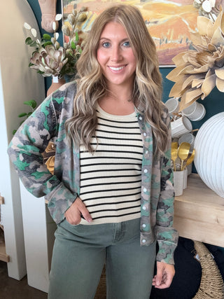 Woman wearing a lightweight faded camouflage button-front cardigan layered over a striped knit tank