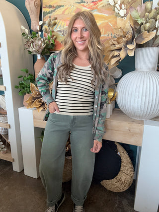 Woman wearing a lightweight faded camouflage button-front cardigan layered over a striped knit tank