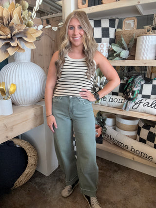 Woman wearing a fitted cream and black striped sleeveless ribbed knit top with olive green pants