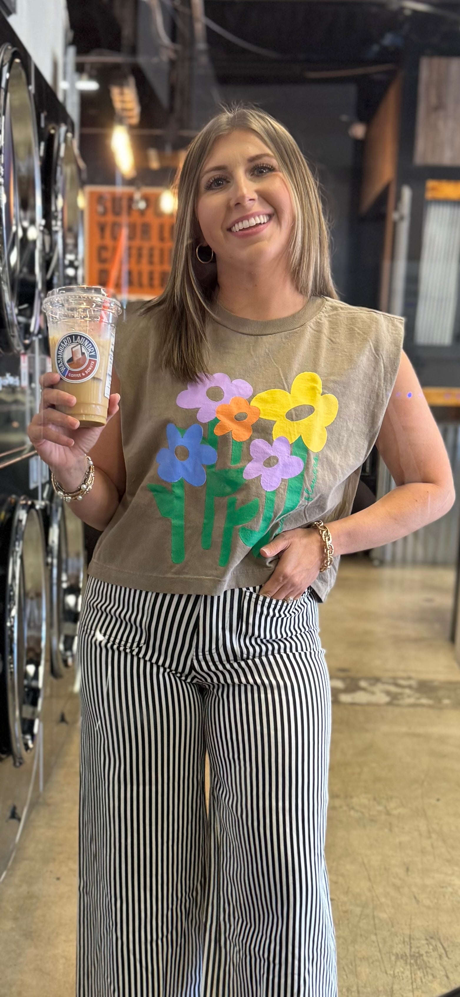 woman wearing taupe muscle tee with colorful floral graphic and no rain no flowers design