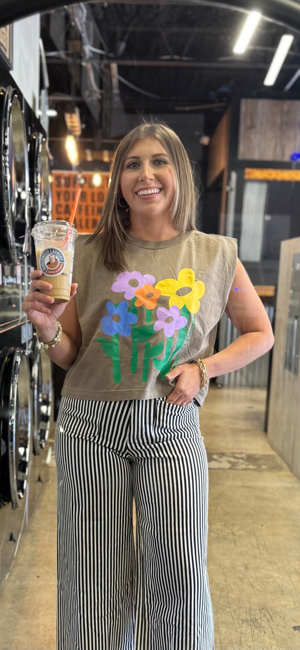 woman wearing taupe muscle tee with colorful floral graphic and no rain no flowers design