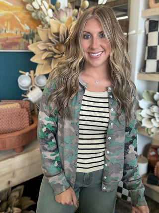 Woman wearing a lightweight faded camouflage button-front cardigan layered over a striped knit tank