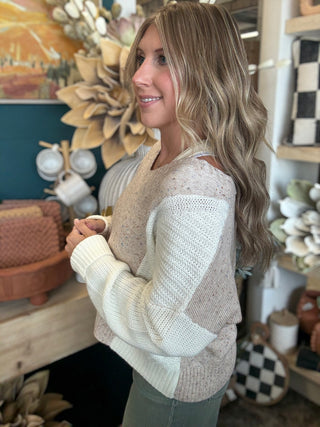 Woman wearing a lace up color block sweater in speckled oatmeal, camel and ivory.