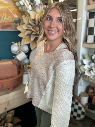 Woman wearing a lace up color block sweater in speckled oatmeal, camel and ivory.