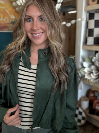 Woman wearing a forest green gathered blouson jacket with high collar, zip front and puff sleeve detailing.