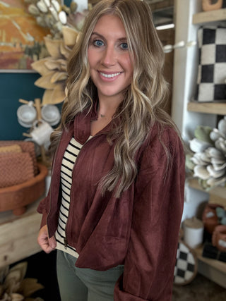 Woman wearing a burgundy gathered blouson jacket with zip front, high neckline and puff sleeves.