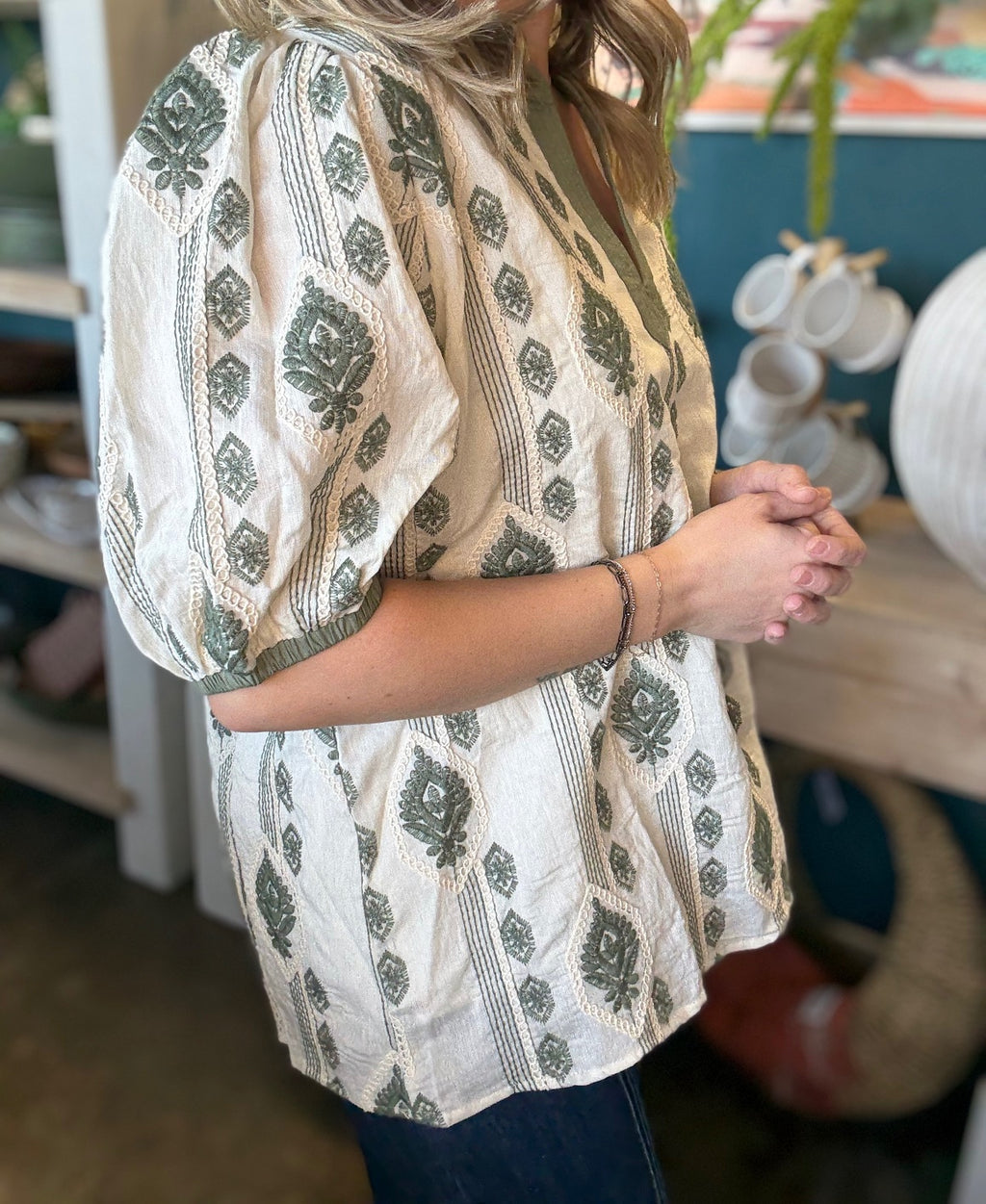 woman wearing ivory and olive printed puff sleeve boutique top with split neckline